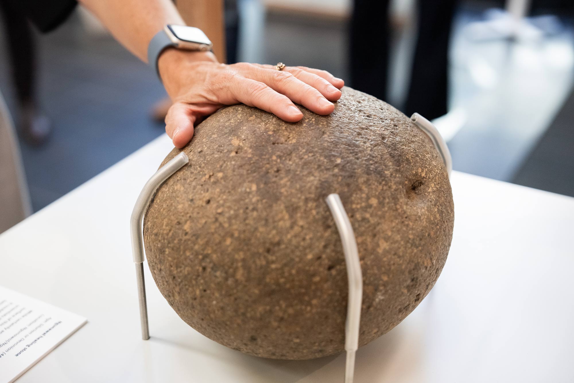 A hand reaching out to touch the Ngunawal healing stone at the Rocks that Shape Australia exhibition
