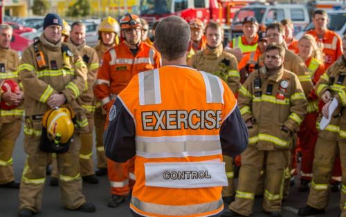 A man wearing a high vis vest talking to a group of emergency workers